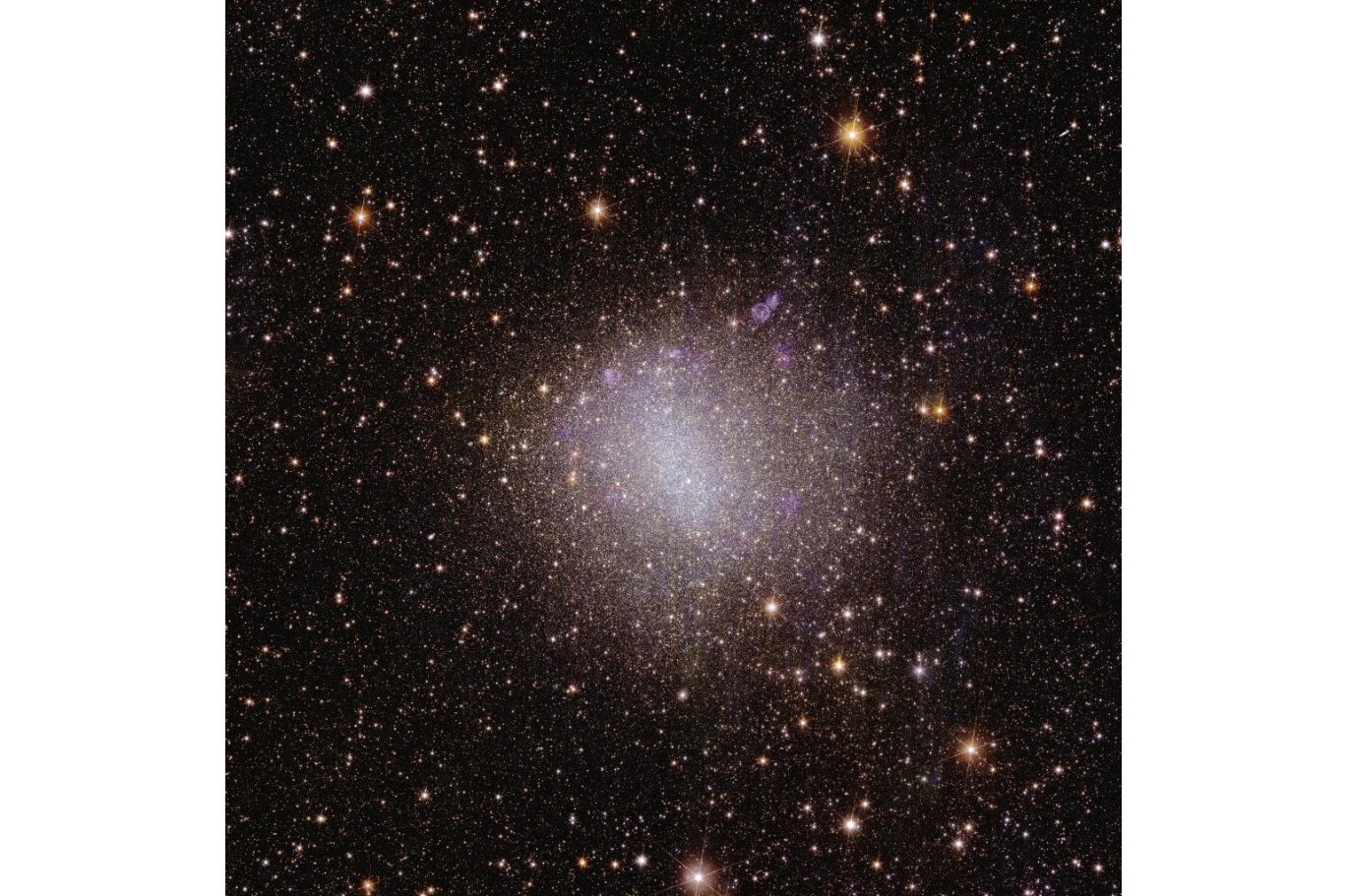 A sparkly pinkish and white blob of light in the center of the image, surrounded by a millions of light specks representing distant cosmic objects.
