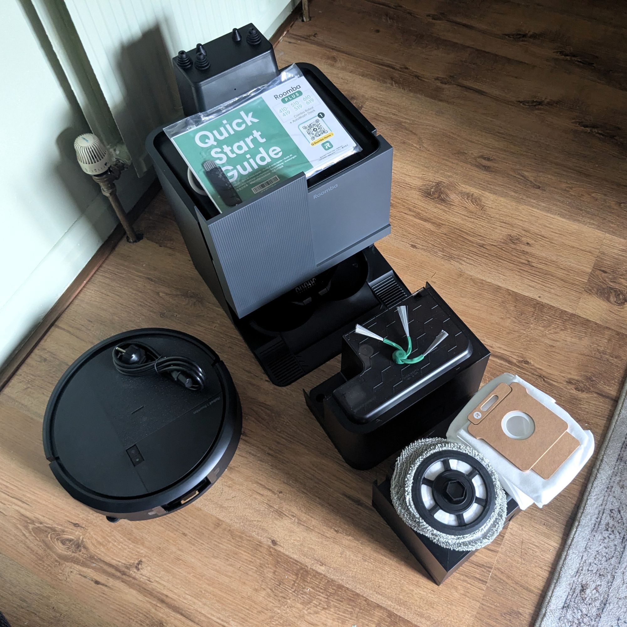 iRobot Roomba Plus 415 Combo components laid out on wooden floors