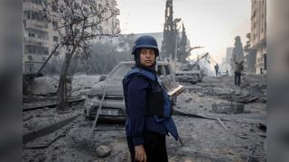 Journalist Samar-Abu-Elouf stands in front of bomb wreckage 