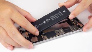 An iPhone with its display removed and battery partially removed