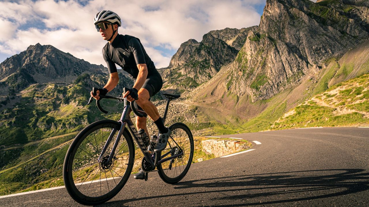 A man riding the Giant Defy Advanced SL road bike on a road in the mountains