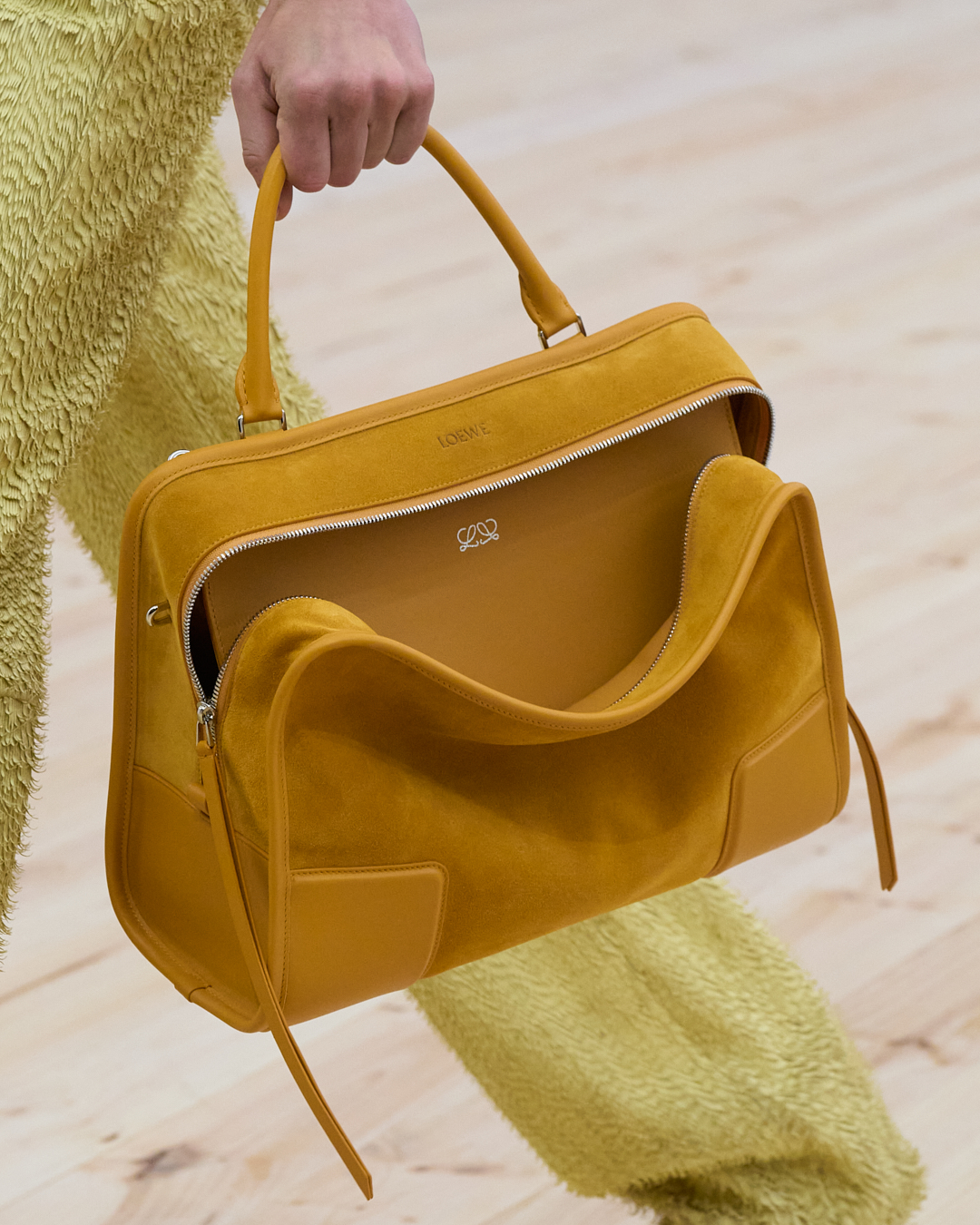 A fall/winter 2026 runway model carrying a slouchy yellow handbag.