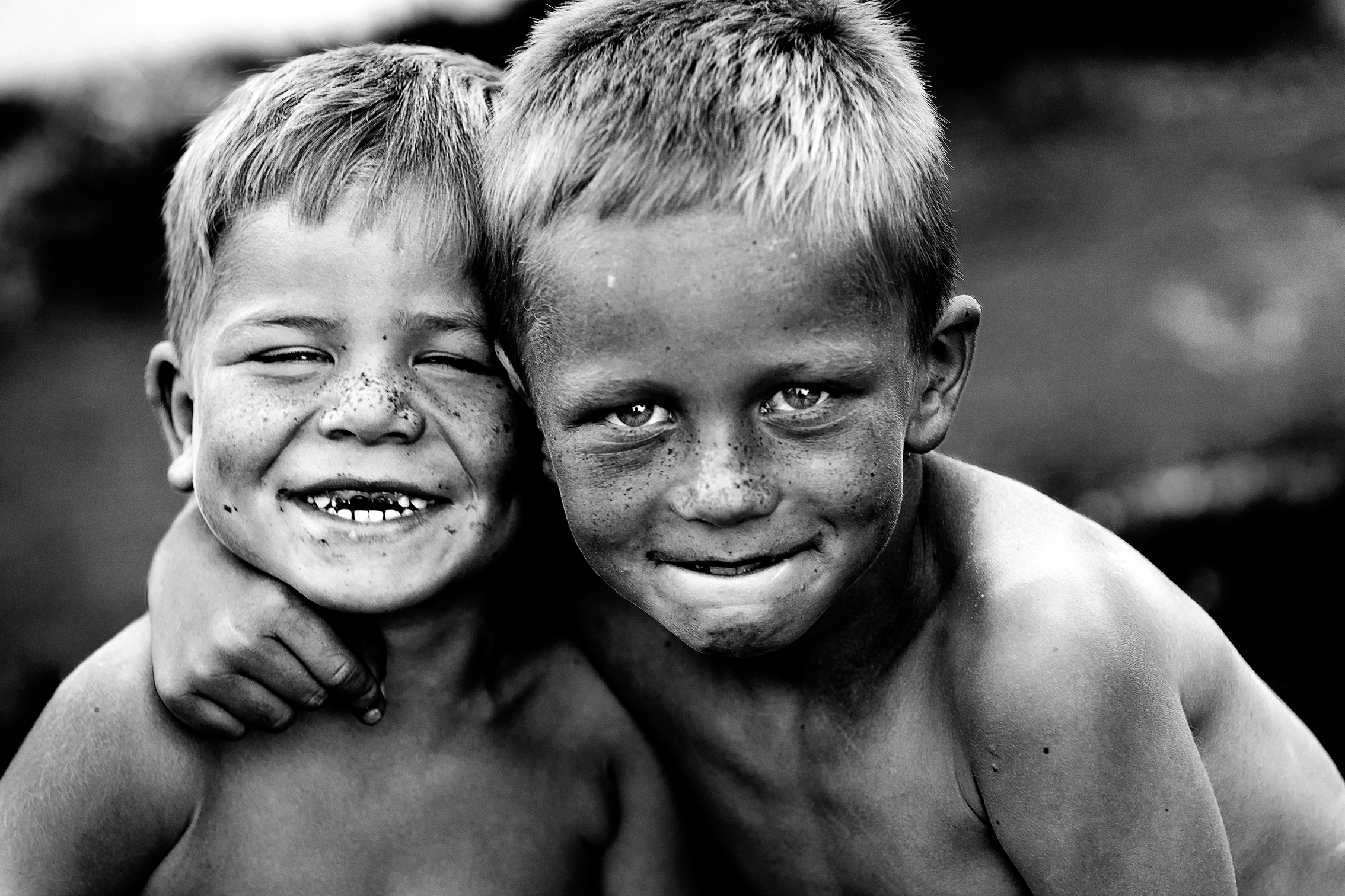 Two young boys with short hair, smiling, covered in dirt