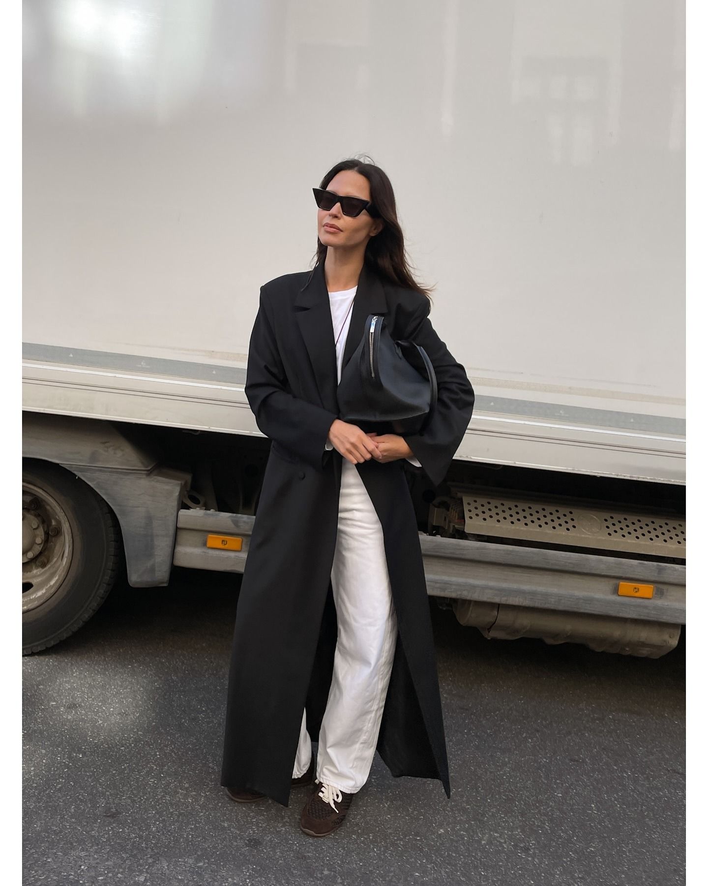 Woman wearing white jeans with with t-shirt, black coat, and brown suede.