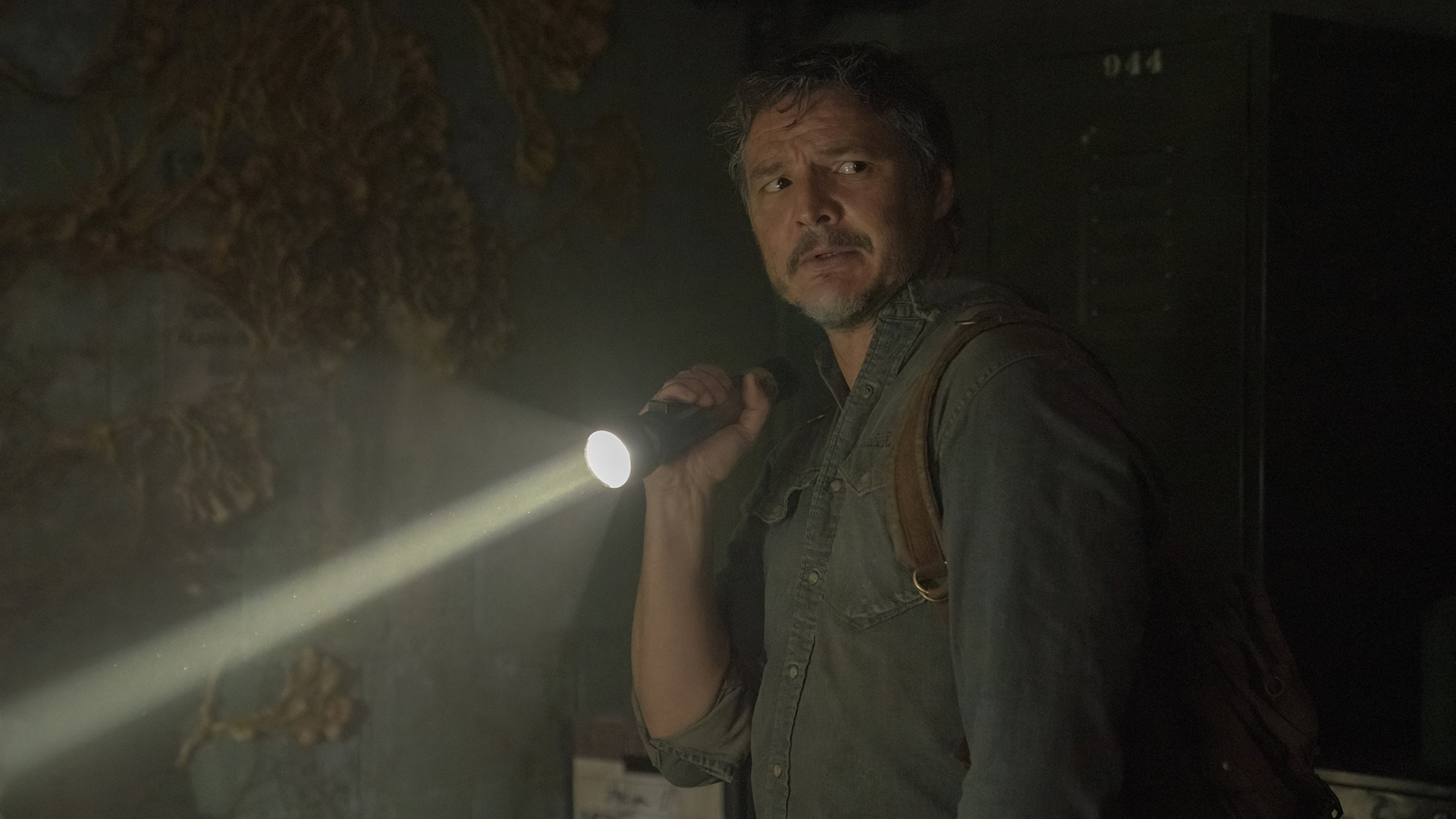 Joel shines a flashlight in a dark room in The Last of Us season 1