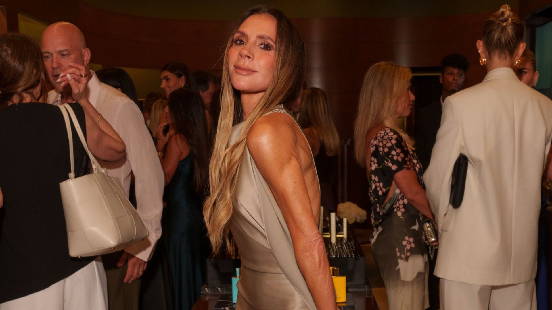 Victoria Beckham wears a neutral dress with pink satin heels.
