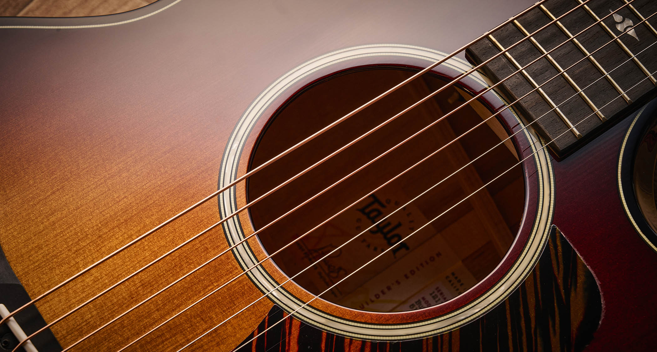 Taylor Builder’s Edition 514ce Kona Burst pictured against a wooden floor and patterned rug.