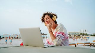 A woman on the beach with a laptop