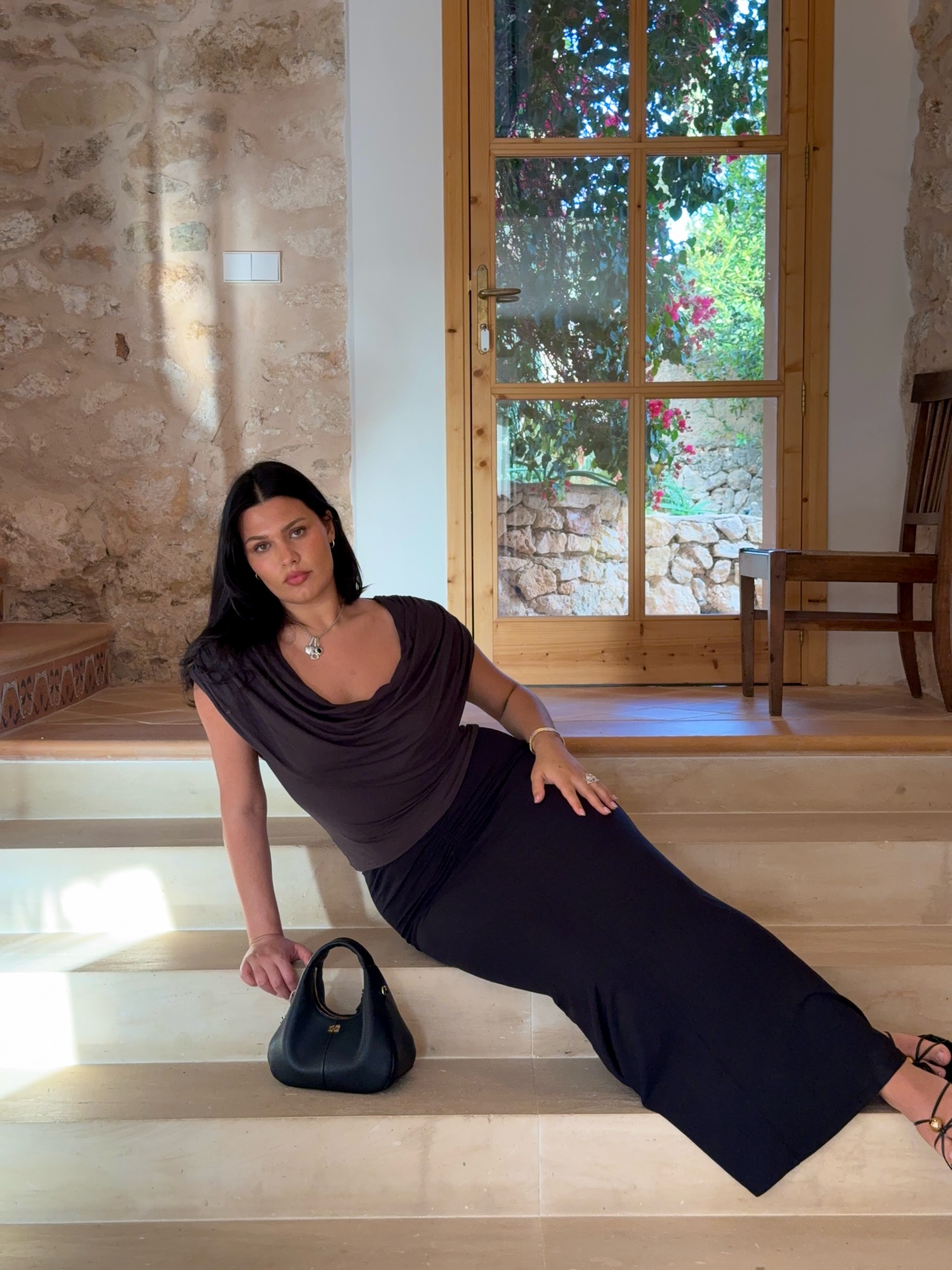An image of @isabellecoheen wearing a quintessential Mallorca summer outfit of a draped top and black maxi skirt