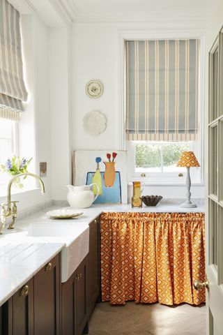 Small kitchen with orange sink skirt by Vanessa Arbuthnott