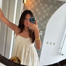 Influencer Sara Ramén wears a white lace dress and a gold bangle. 