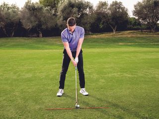 Gary Munro demonstrating the correct set-up for long iron shots using alignment sticks