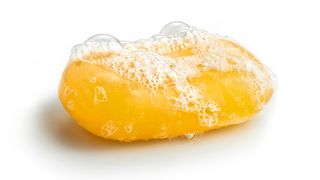 A foamy, yellow bar of soap against a white background