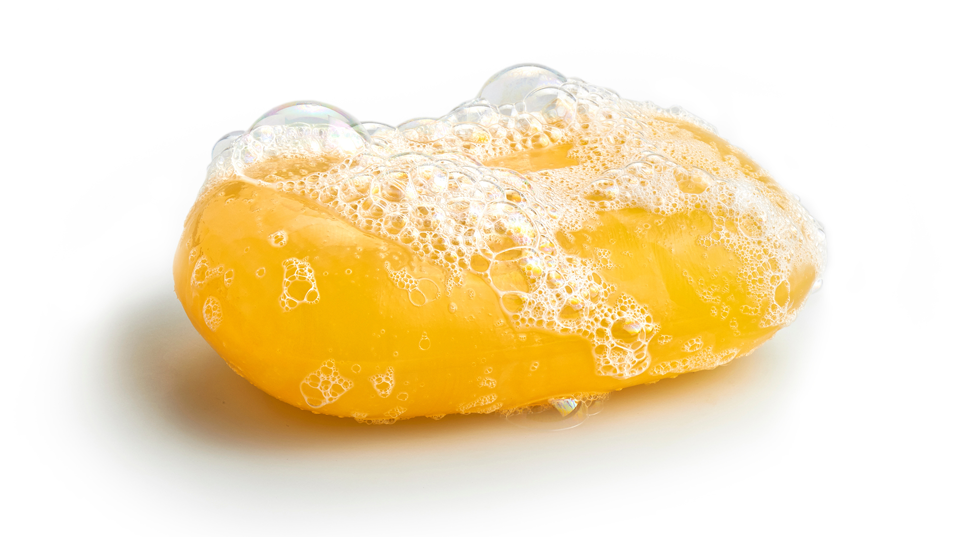 A foamy, yellow bar of soap against a white background