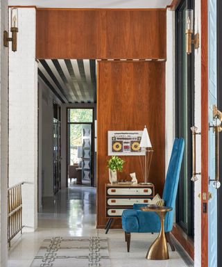 Mid-century modern entryway with a retro dresser and striking blue upholstered accent chair