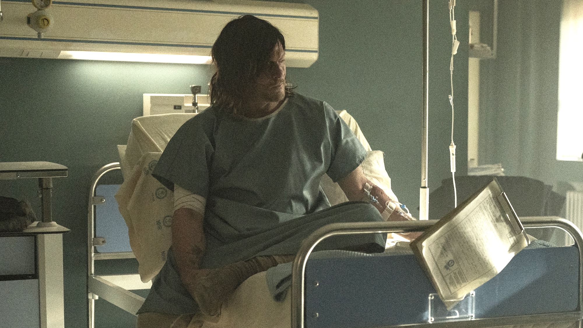 Norman Reedus' Daryl wearing hospital gown and sitting in a hospital bed in a hospital in The Walking Dead: Daryl Dixon Season 4