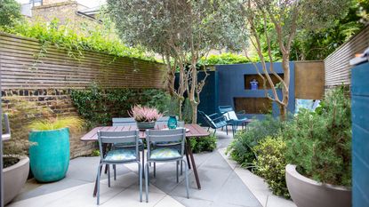 Small paved garden split into zones with blue back wall