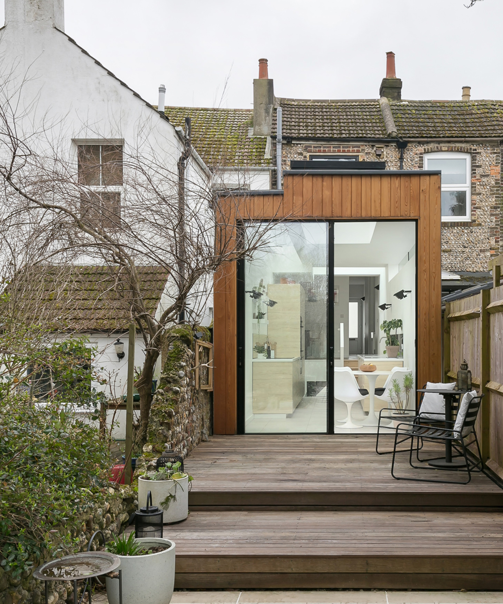 Exterior view of small house extension idea with timber cladding and outside decked area