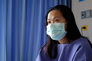 A stock photo of a patient in the hospital wearing a face mask.