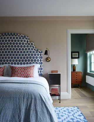 traditional bedroom with neutral wall, blue patterned headboard and blue patterned rug
