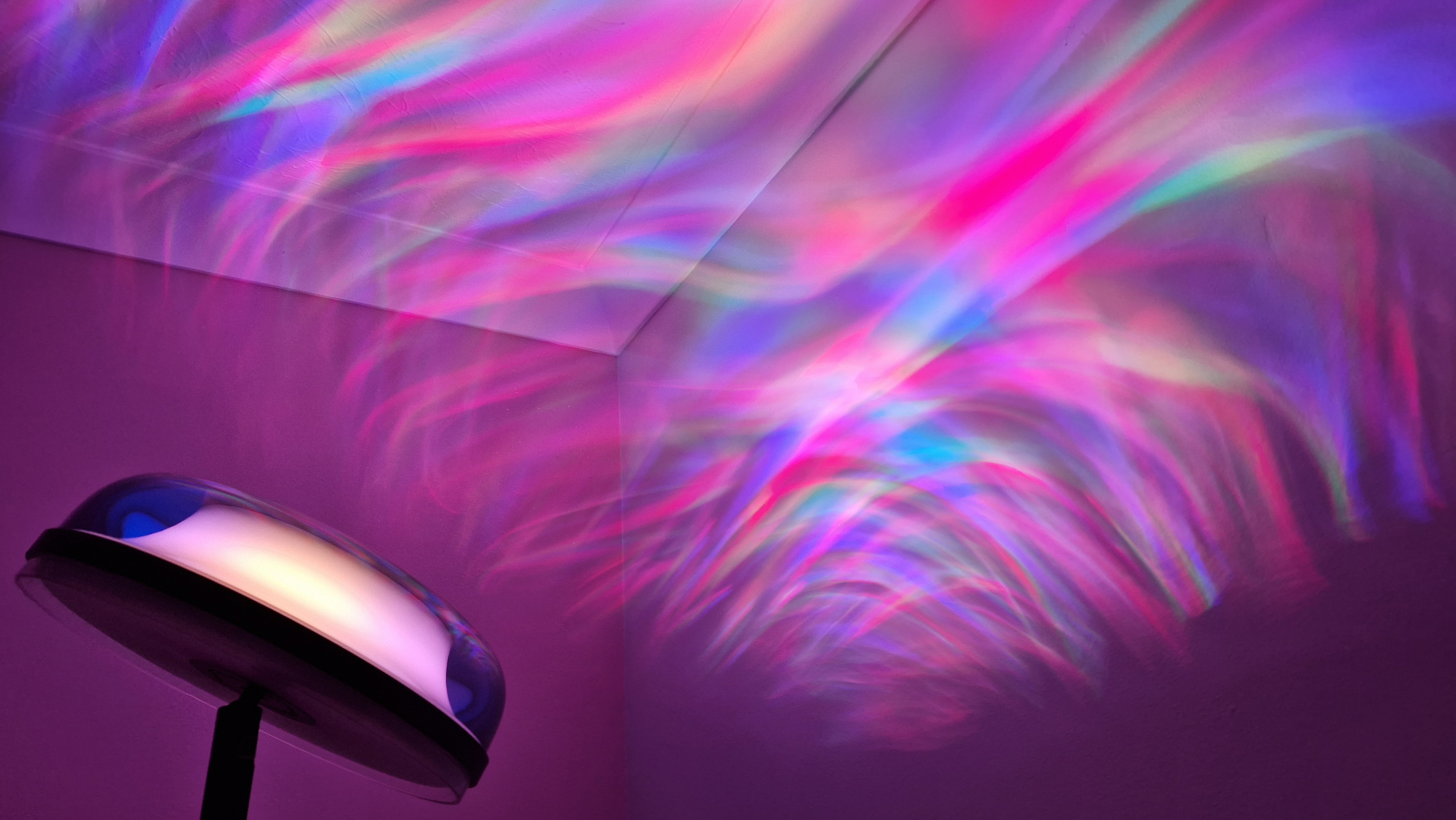 The Govee Uplighter Floor Lamp is projecting rainbow swirls onto a bedroom wall and ceiling.