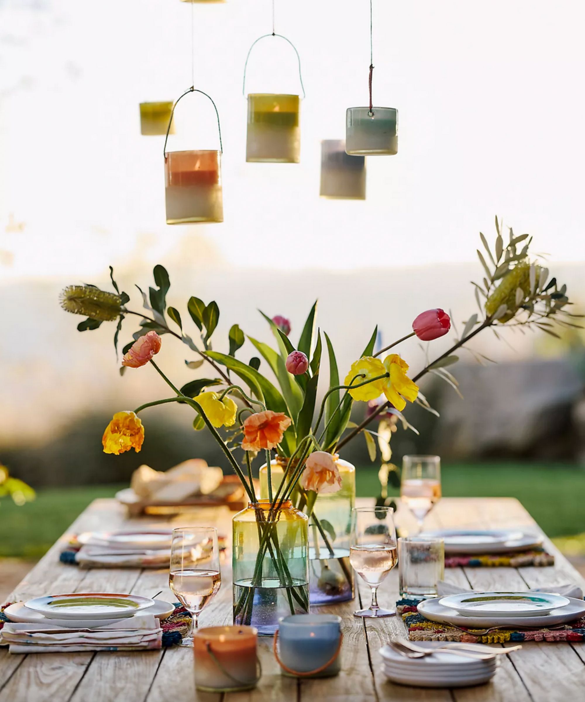 Outdoor table setting with flowers and candles hanging above