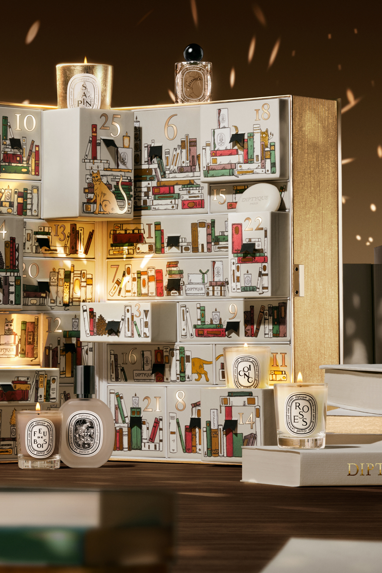 A gold advent calendar with glass candles room sprays, diffusers, and more
