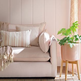 Pink linen sofa in front of pink panelled wall