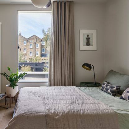 A neutral bedroom with taupe curtains and sage green and taupe bedding