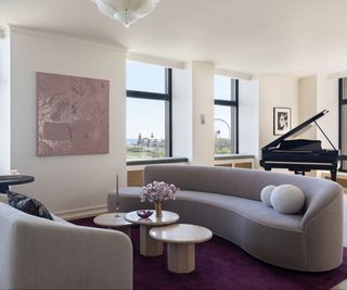 living room with gray curved sofas three round coffee tables and grand piano in background
