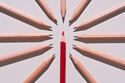 a red pencil surrounded by 11 regular pencils