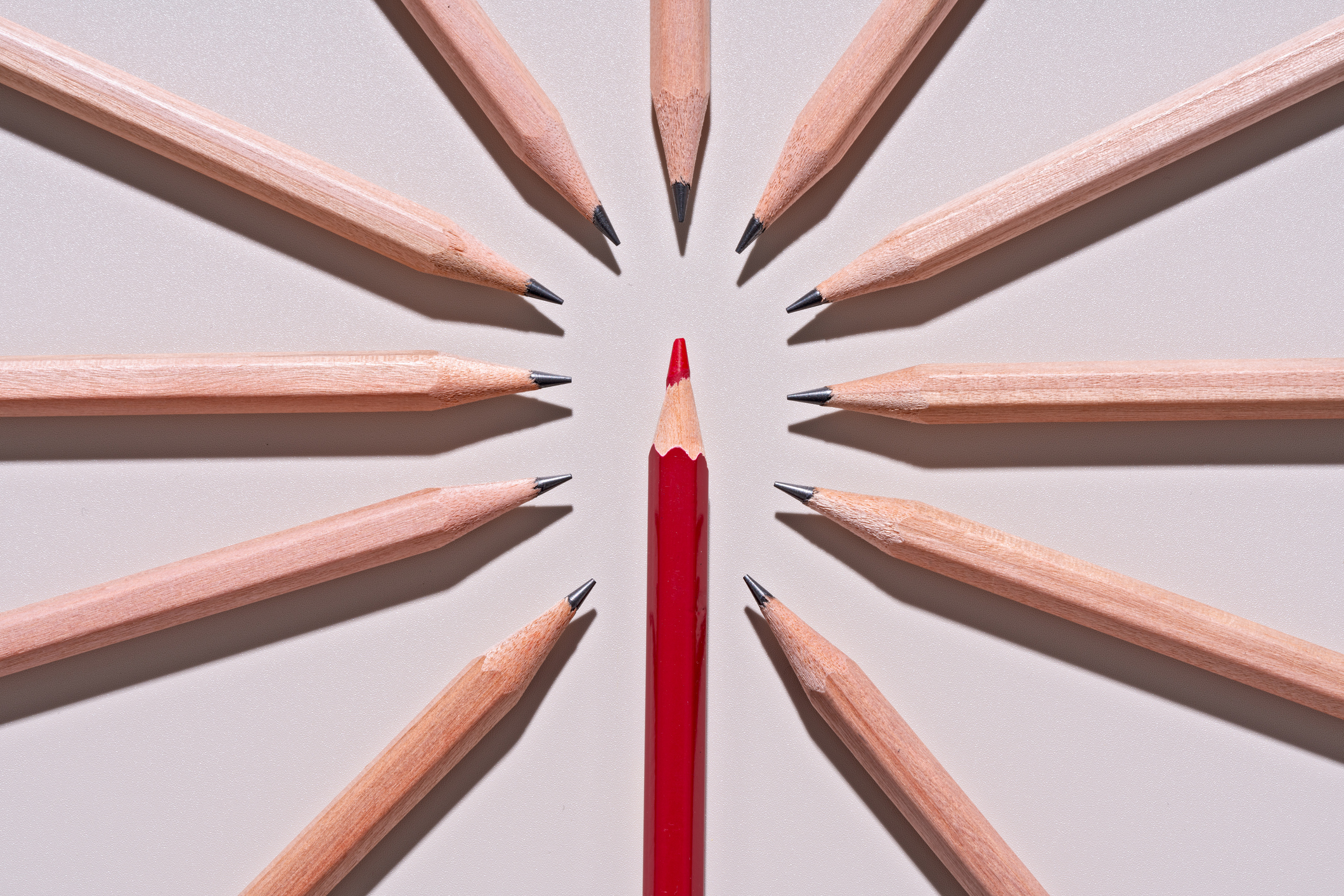 a red pencil surrounded by 11 regular pencils