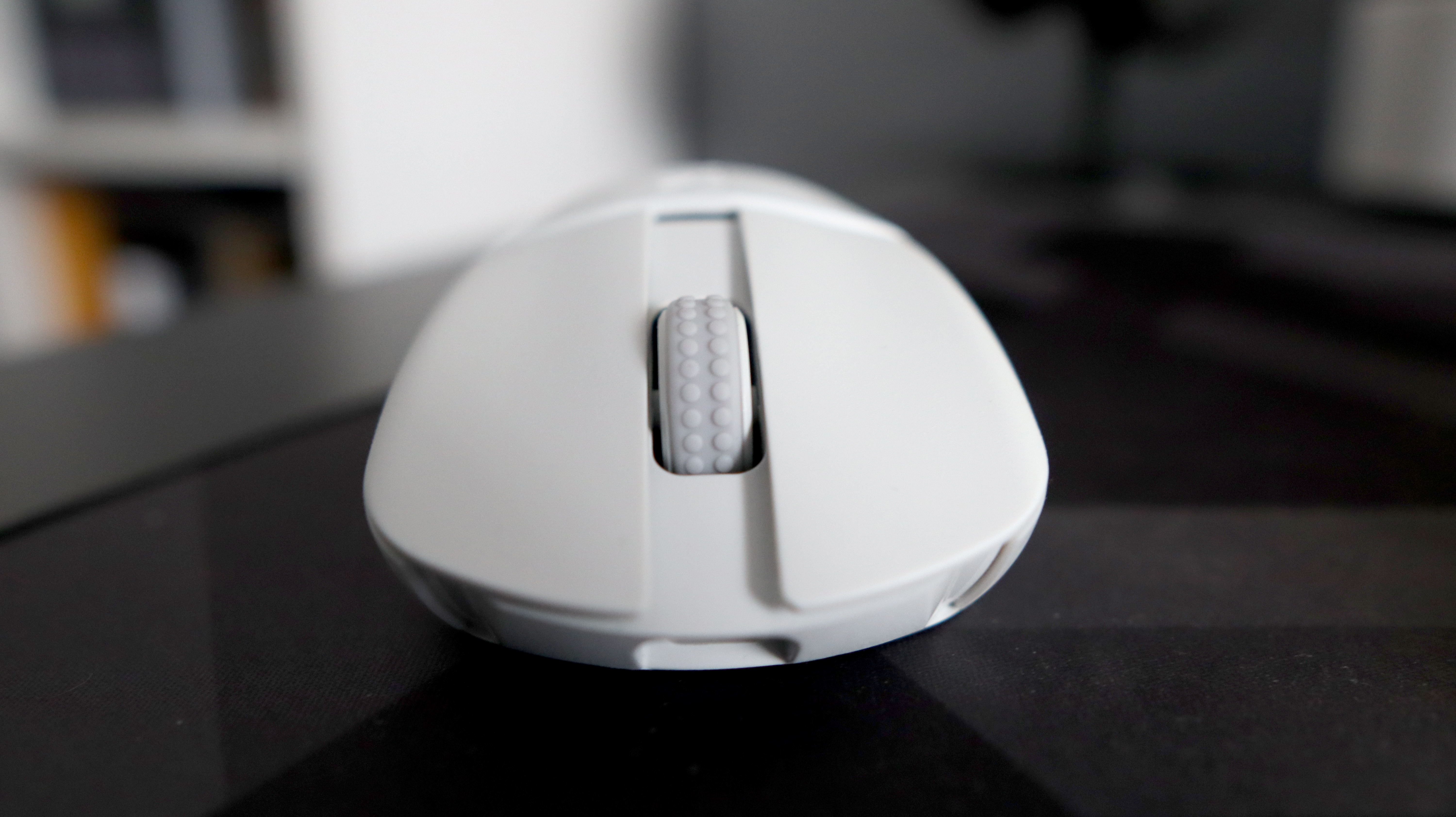 An NZXT Lift Elite Wireless gaming mouse in white set-up on a desk.