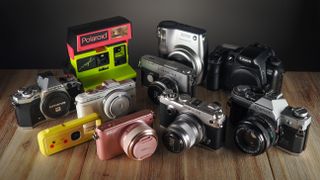 A selection of analog, digital, instant and mirrorless cameras on a wooden surface