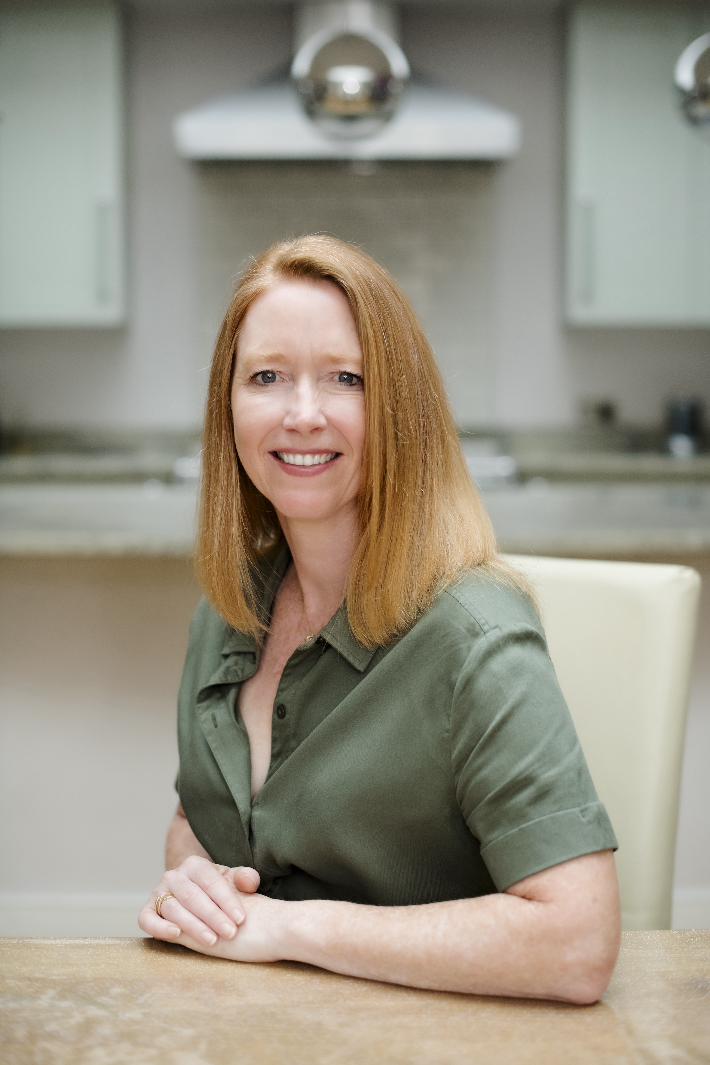 woman with red hair wearing a green shirt sitting at a table