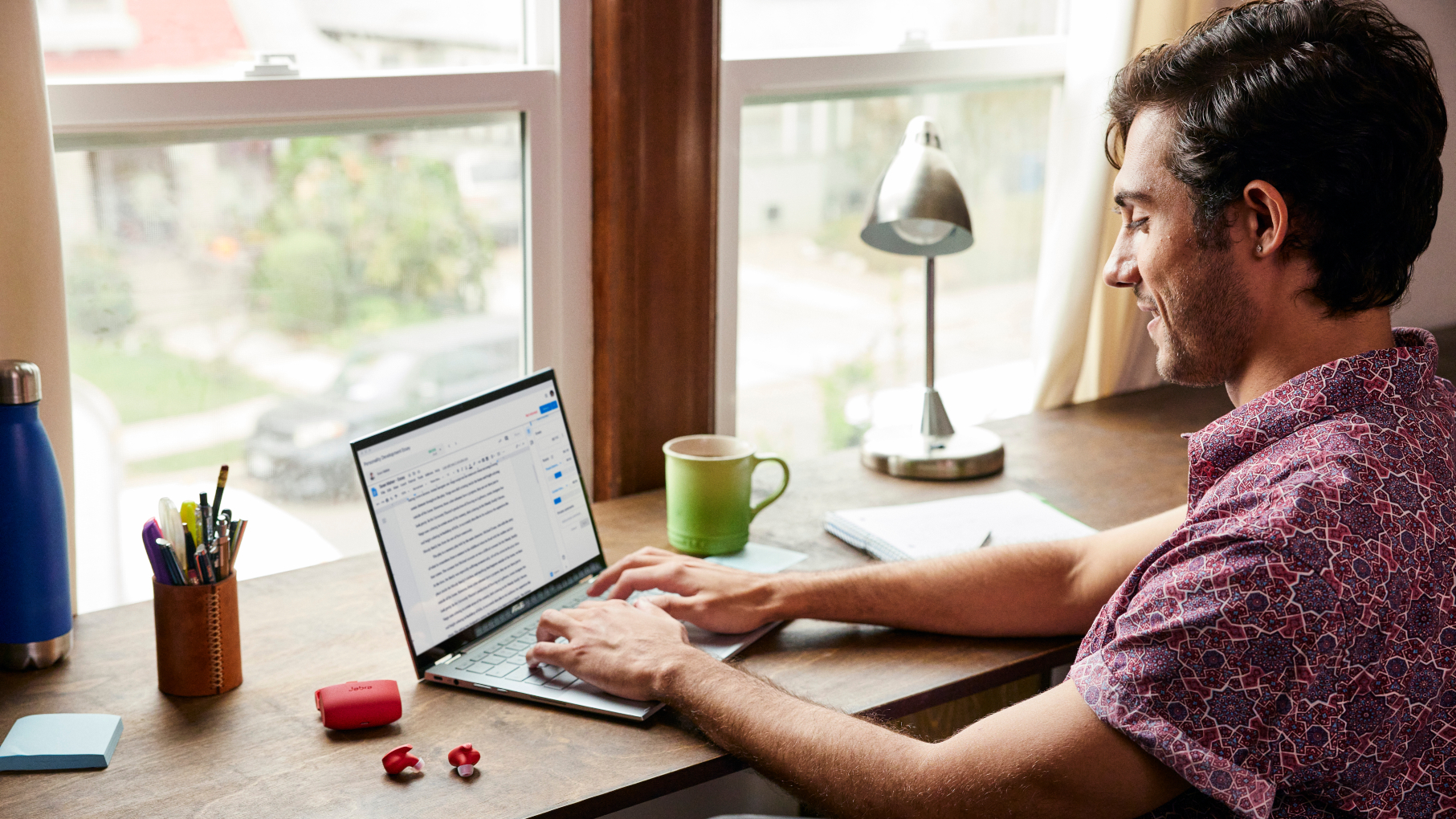 PErson using Asus Flip on desk next to headphones and stationary