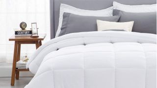Bedsure Down Alternative Quilted Comforter review: The comforter shown in white, folded neatly over a bed with a light gray headboard and gray pillows