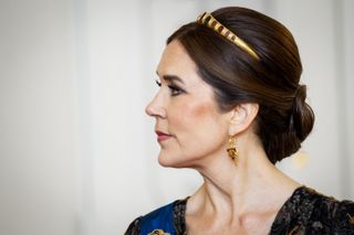 Queen Mary of Denmark turning to the right wearing a black lace dress and gold tiara