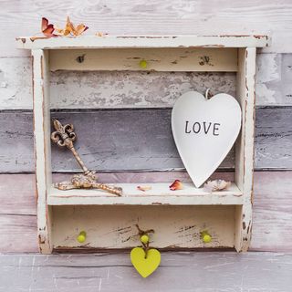 Distressed Country Cottage Wall Shelf with heart-shaped ornaments against rustic pink and grey wall