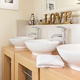 bathroom with clean lines and subtle cream shades and three matching basins and gold love sign