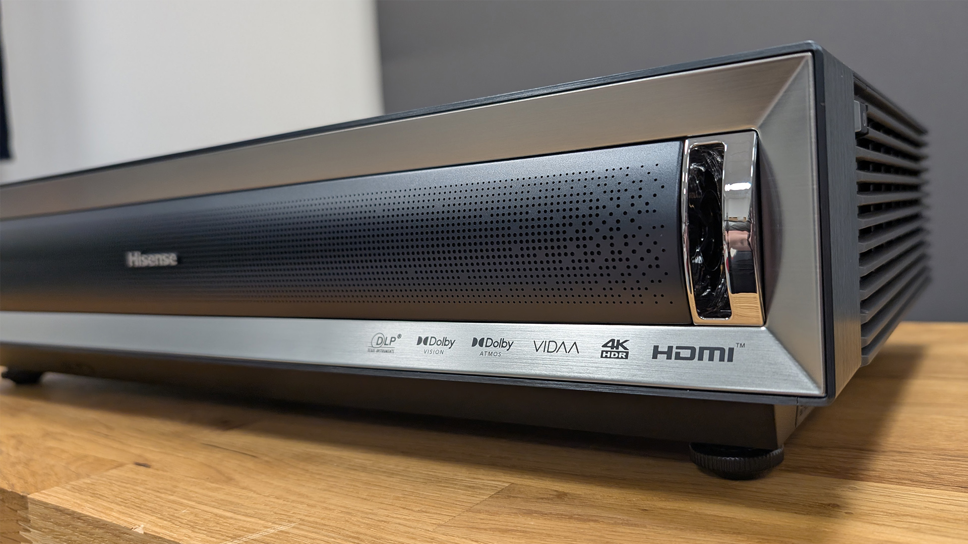 Hisense PX3 ultra short throw projector on wooden AV rack against white and grey walls