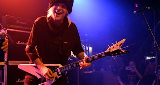 Michael Schenker solos on his black-and-white Dean V, with a bank of Marshall amps in the background.