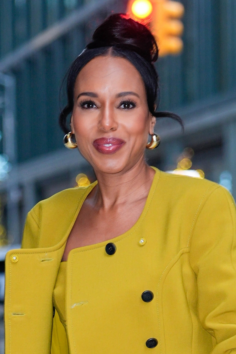 Kerry Washington is seen with a high updo hairstyle and wearing gold earrings and a green/yellow coat. on December 10, 2025, in New York City.