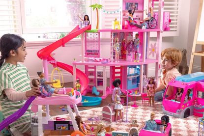 Barbie Dreamhouse Black Friday deal: a girl and boy smile at each other as they play with the doll's house