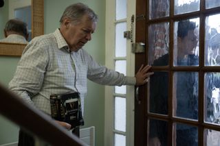 Richard (George Costigan) stands in his hallway behind his front door, clutching a four-pack of Guinness