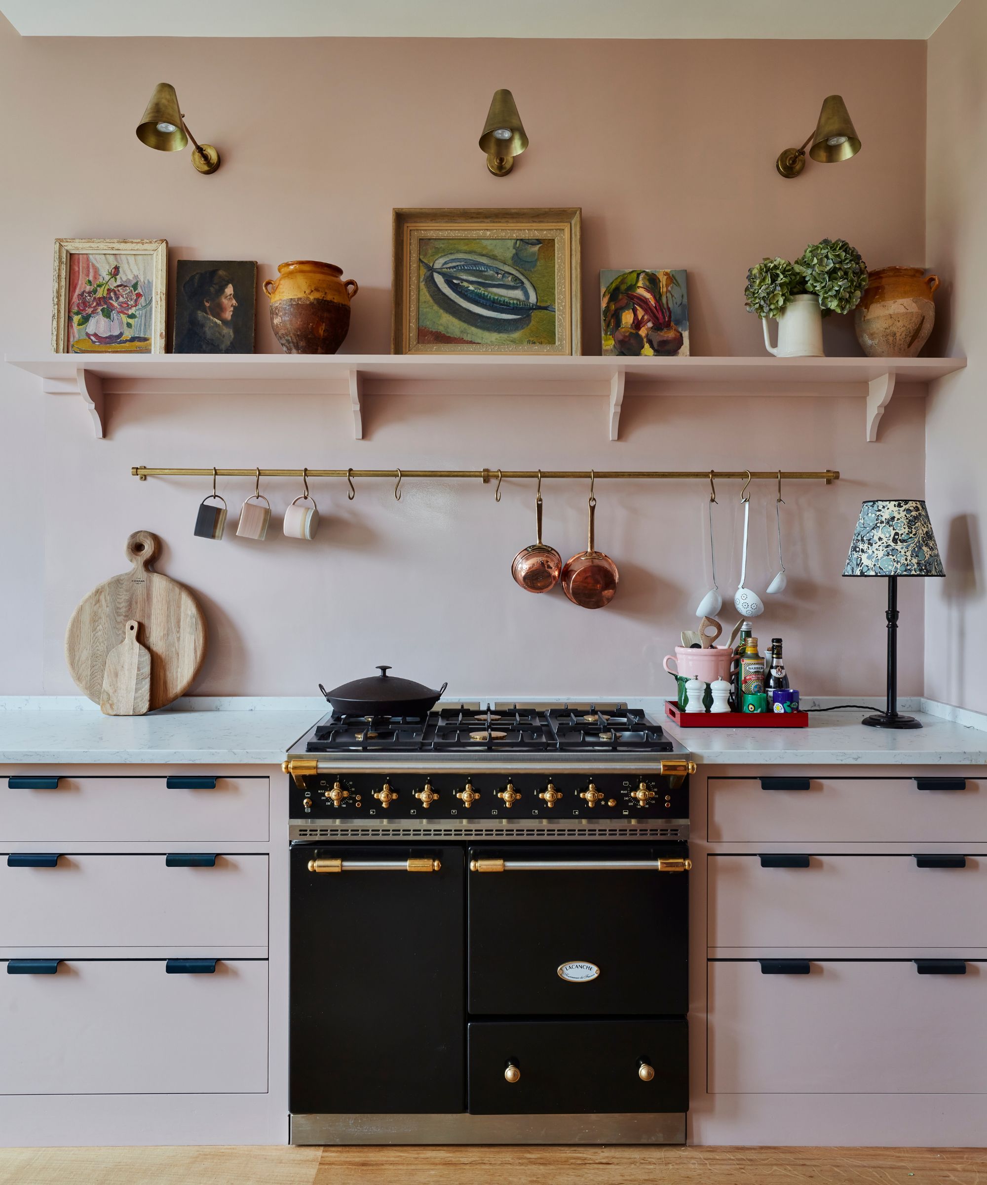 Pink kitchen by Sarah Brown interiors featuring oil paintings styled on a shelf