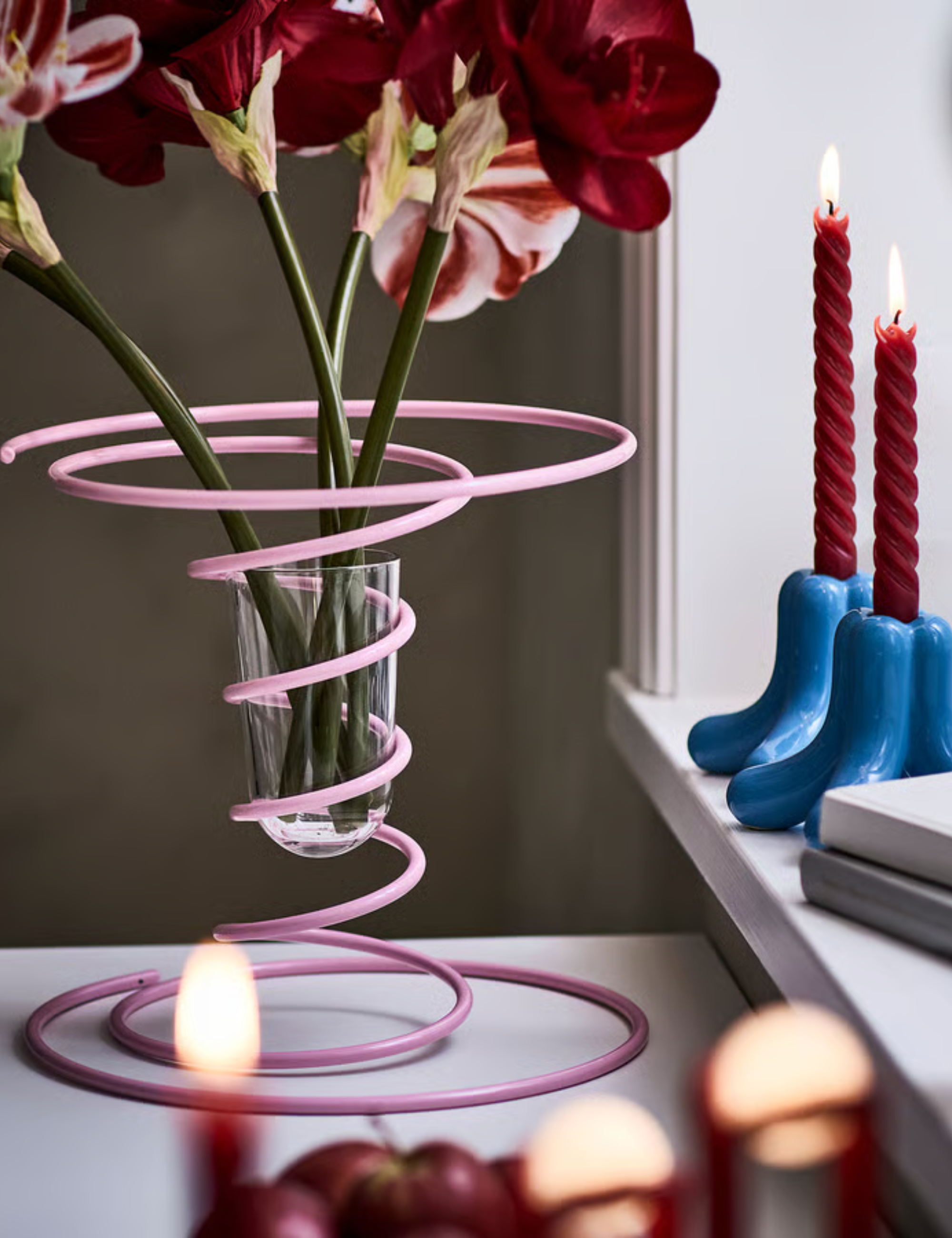 Eclectic tablescape featuring a Rebel Pink spiral vase and blue ceramic taper holders