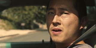 Steven Yeun looking out the window of his car