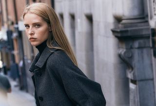 An H&M model wearing a charcoal wool coat with a turtleneck and matching trousers.