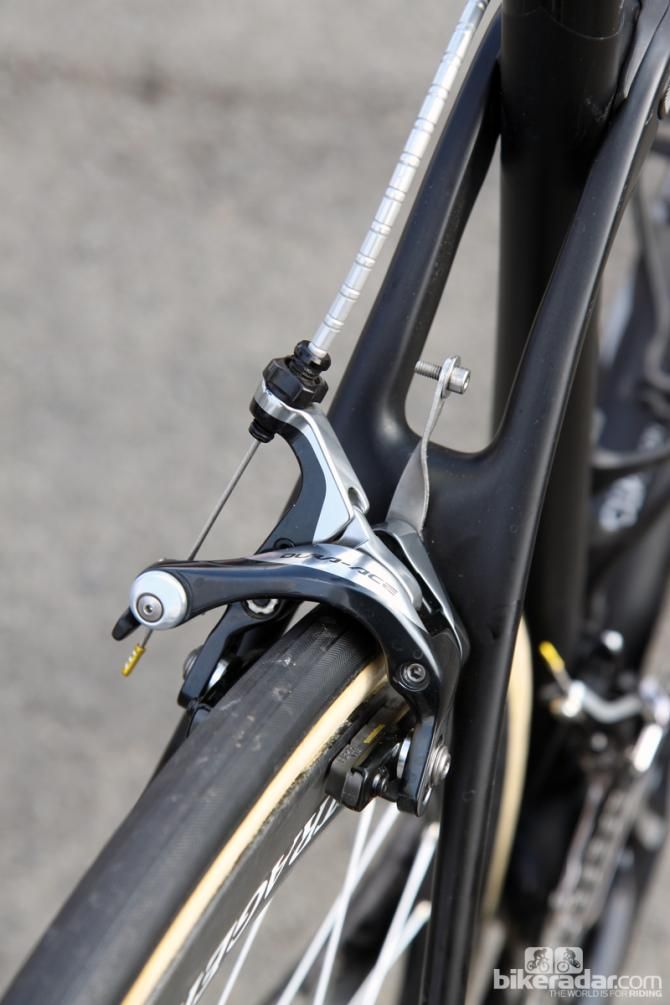 A stainless steel number plate holder is sandwiched between the Shimano Dura-Ace BR-9000 brake caliper and brake bridge.